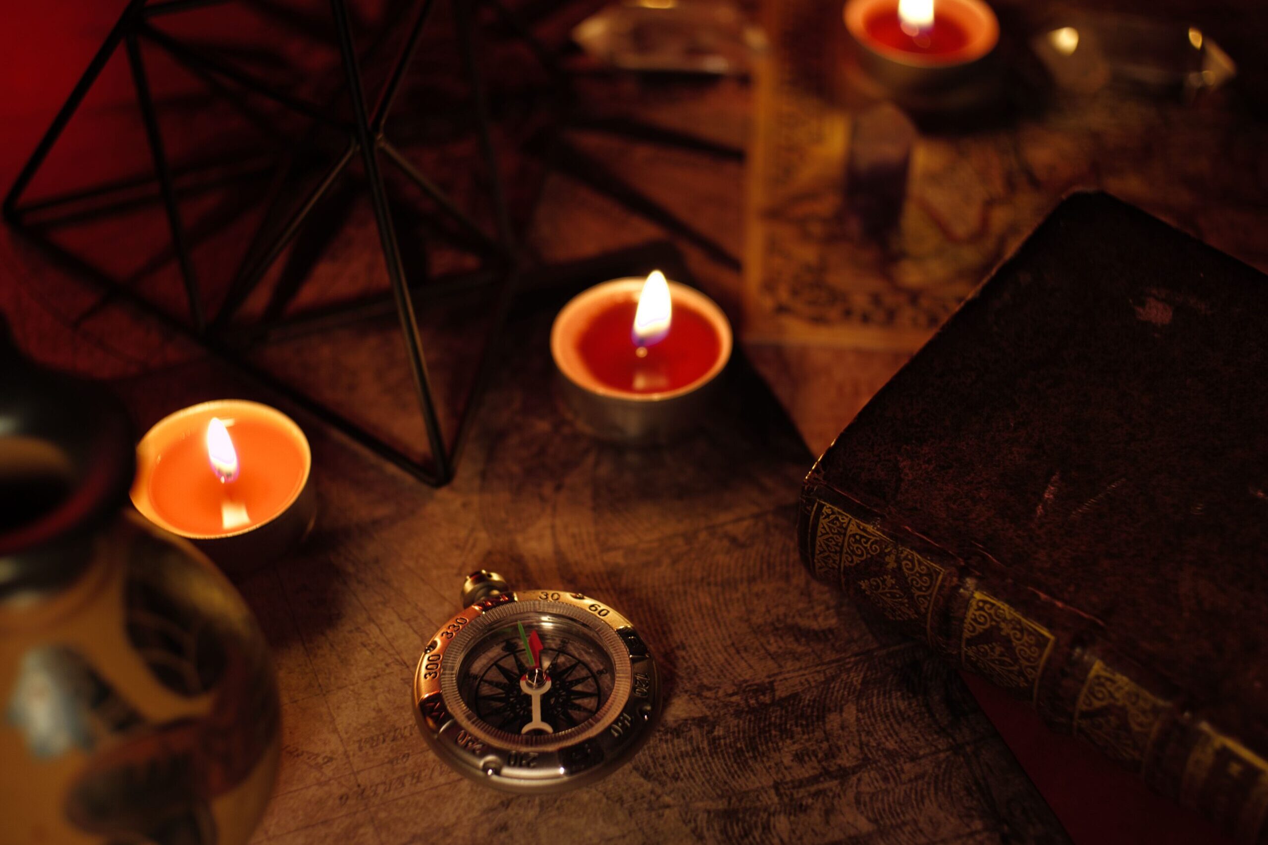 A cozy still life featuring candles, a compass, a map, and a vintage book creating a warm and inviting atmosphere.
